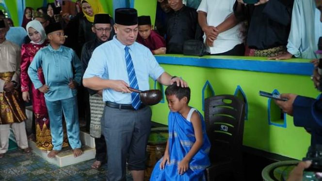 
					Bupati Lingga memandikan anak saat tradisi Mandi Safar di Desa Resun