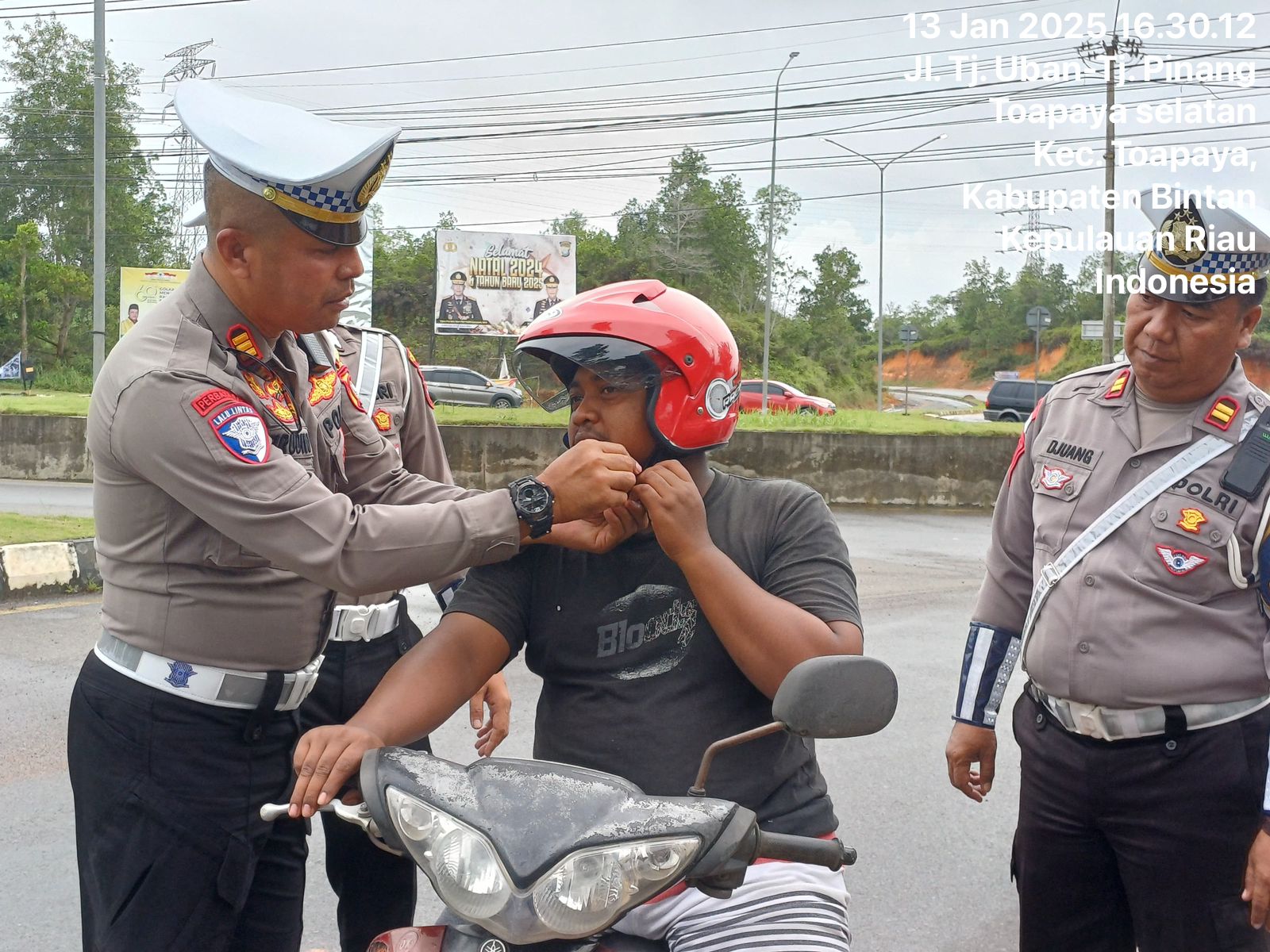 Kasatlantas Polres Bintan AKP Firudin, saat terjun langsung berikan helm gratis ke pengguna kendaraan roda dua, Senin (13/01/2025).