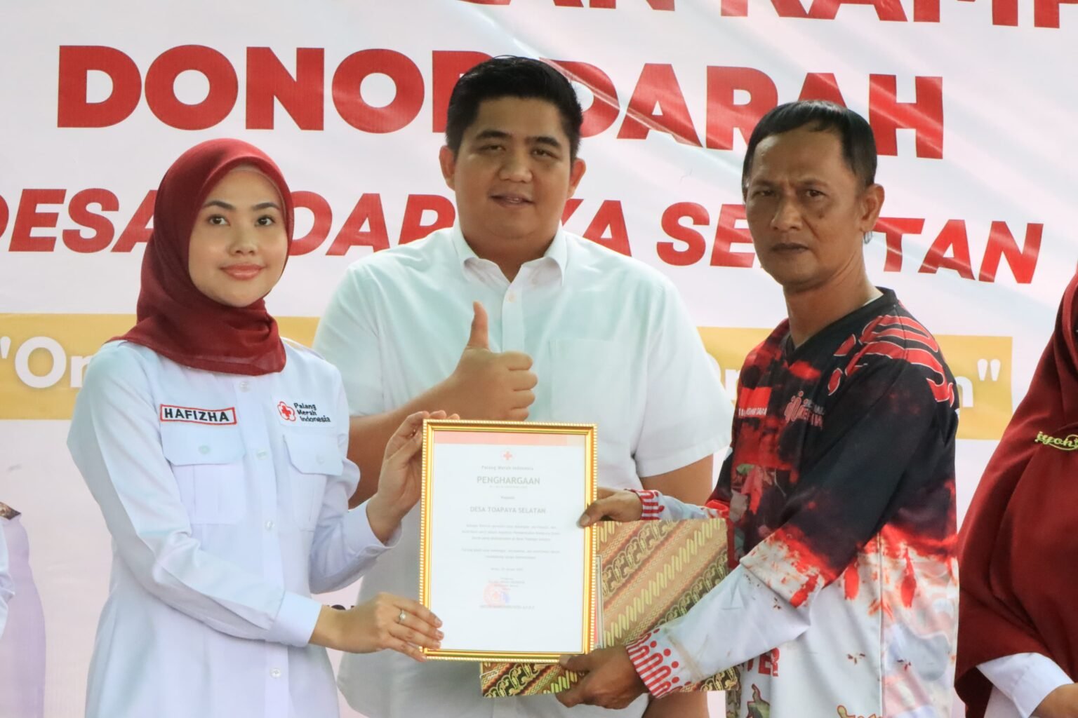 Ketua PMI Bintan Hafizha Rahmadhani didampingi Bupati Bintan Roby Kurniawan menyerahkan penghargaan kampung donor darah kepada Kepala Desa Toapaya Selatan Suhenda